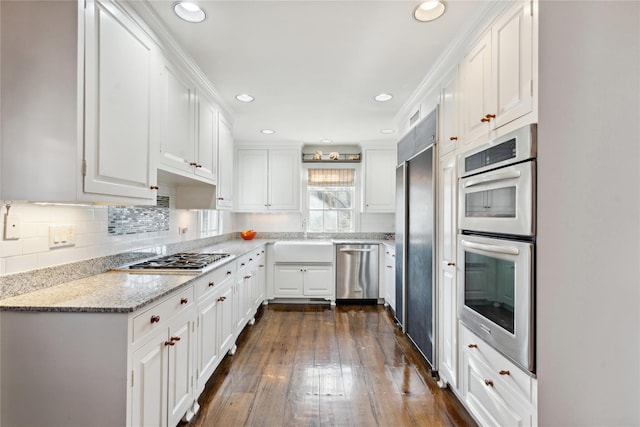 kitchen with decorative backsplash, dark wood-style flooring, appliances with stainless steel finishes, and white cabinetry