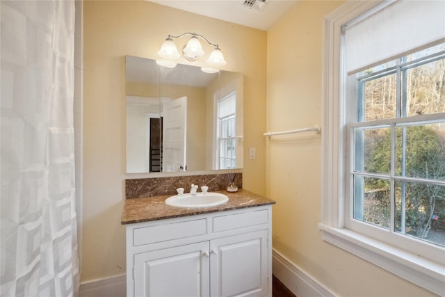 full bath featuring baseboards, vanity, visible vents, and plenty of natural light