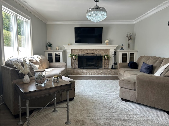 living area featuring a brick fireplace, wood finished floors, a chandelier, and crown molding