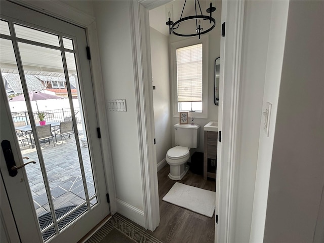 bathroom featuring an inviting chandelier, wood finished floors, toilet, vanity, and baseboards