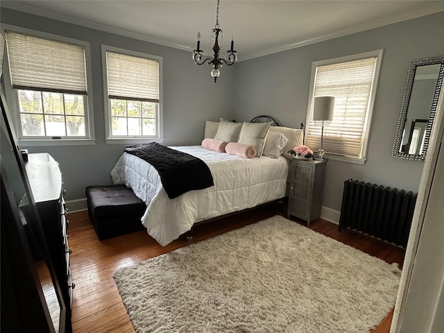 bedroom with radiator, wood finished floors, ornamental molding, baseboards, and a notable chandelier