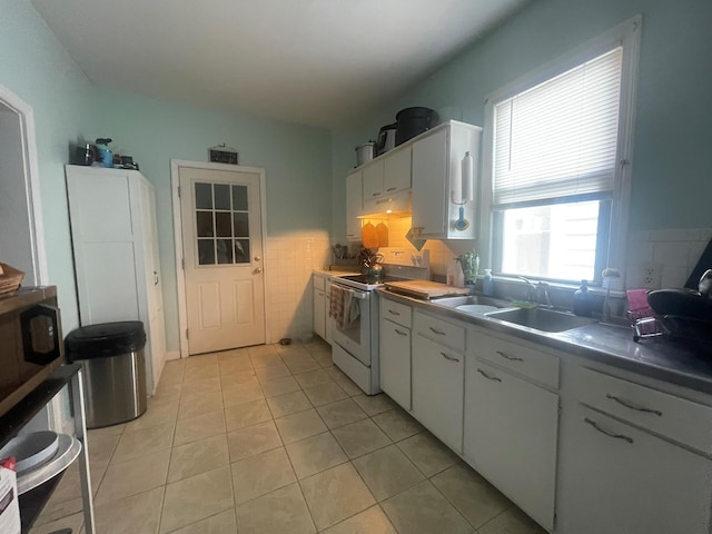 kitchen with light tile patterned floors, white cabinets, a sink, under cabinet range hood, and electric stove
