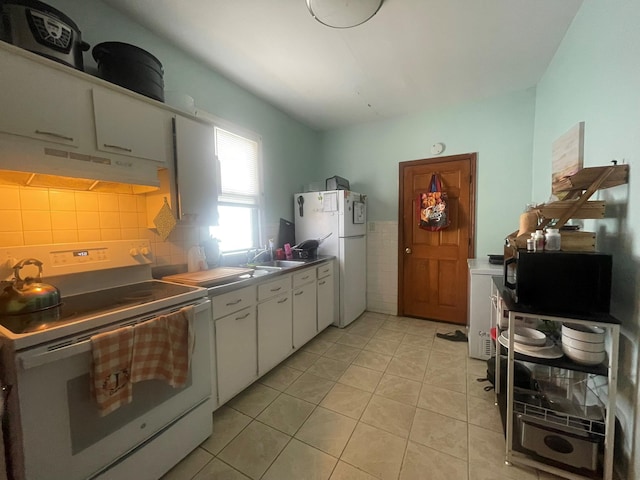 kitchen with tile walls, under cabinet range hood, light tile patterned floors, white appliances, and white cabinets