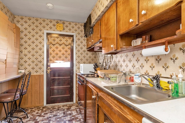 3530 Long Beach Rd Unit 68, Oceanside, NY 11572 - kitchen with brown cabinets, a sink, light countertops, range with gas stovetop, and wallpapered walls