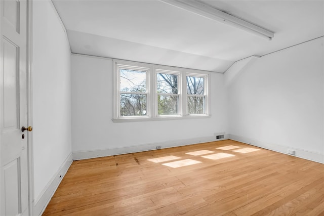 empty room featuring vaulted ceiling, wood finished floors, visible vents, and baseboards