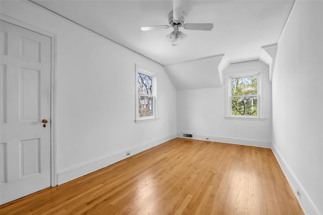 bonus room with light wood-type flooring, ceiling fan, baseboards, lofted ceiling, and visible vents