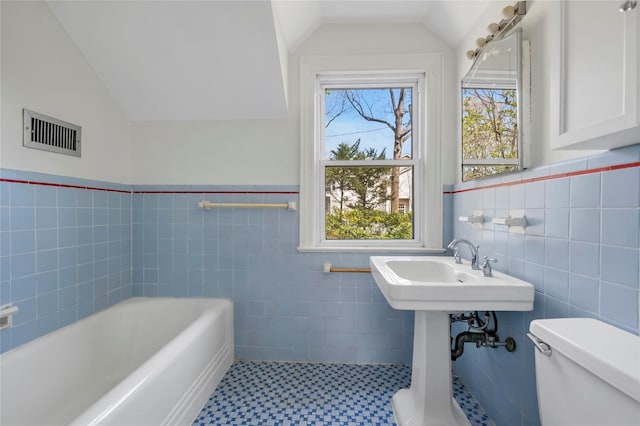 full bathroom featuring vaulted ceiling, visible vents, toilet, tile walls, and a bath