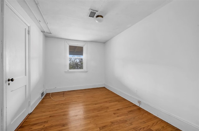 spare room featuring light wood-style flooring, visible vents, and baseboards