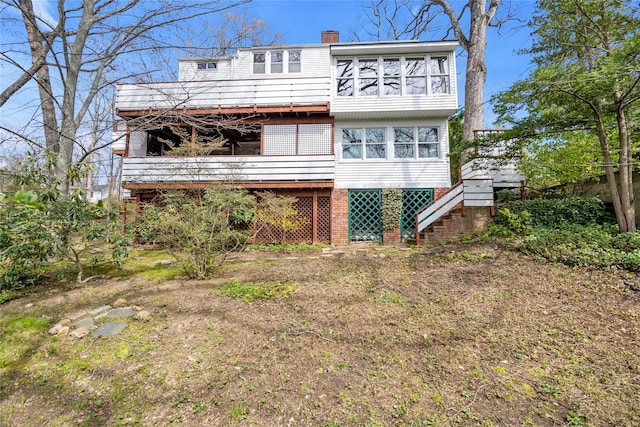 rear view of property featuring a chimney and stairway