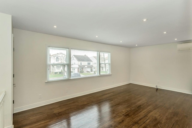 unfurnished room featuring a wall mounted air conditioner, dark wood finished floors, baseboards, and recessed lighting
