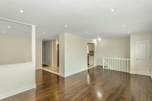 unfurnished room with baseboards, wood finished floors, and recessed lighting