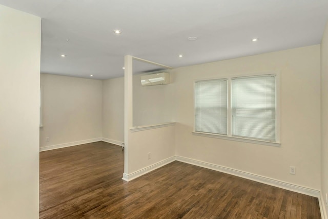 spare room with recessed lighting, baseboards, an AC wall unit, and dark wood-style floors