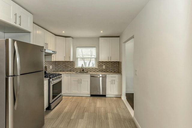 kitchen featuring stainless steel appliances, a sink, backsplash, and white cabinetry
