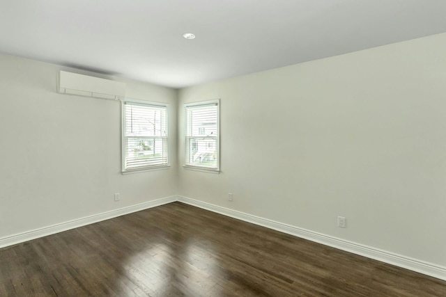 unfurnished room with dark wood finished floors, baseboards, and a wall unit AC