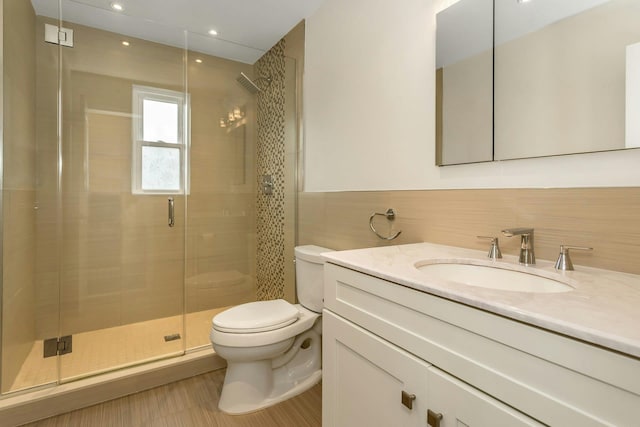 full bathroom featuring a shower stall, toilet, vanity, and tile walls