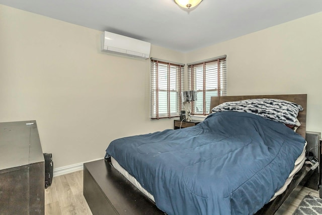 bedroom with an AC wall unit, baseboards, and wood finished floors