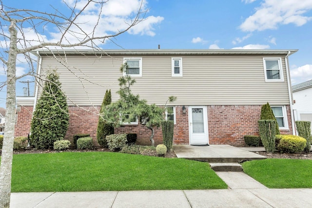 rear view of house featuring brick siding and a lawn