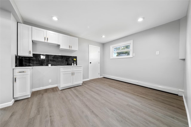 38 Moffitt Blvd, East Islip, NY 11730 - kitchen with baseboard heating, white cabinets, light wood-style floors, tasteful backsplash, and baseboards