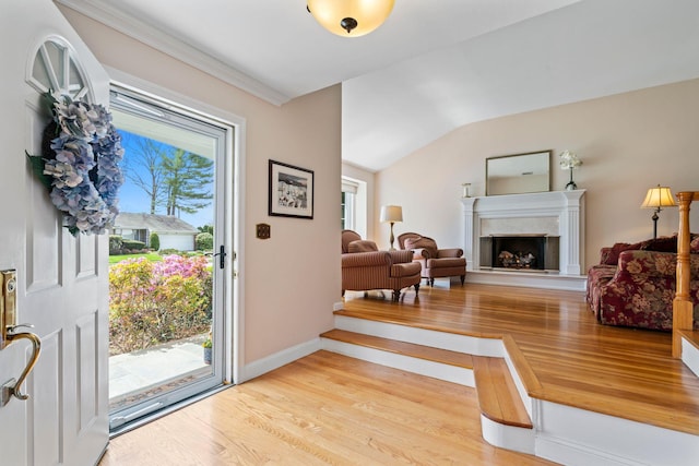 entrance foyer featuring light wood-type flooring, a fireplace with raised hearth, baseboards, and a healthy amount of sunlight