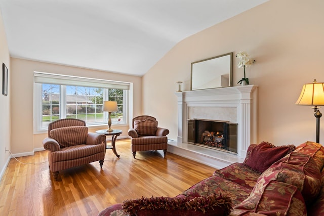 living area with baseboards, lofted ceiling, wood finished floors, and a fireplace