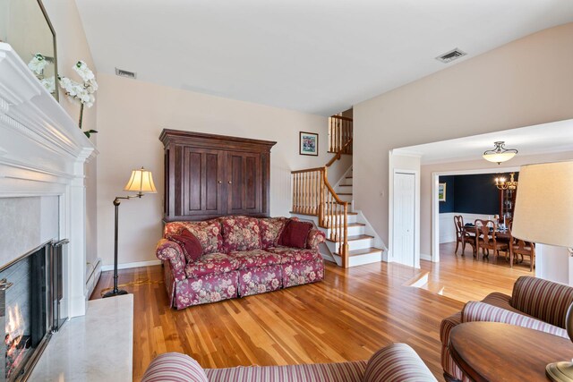 living room with a baseboard radiator, light wood-style floors, stairway, and visible vents