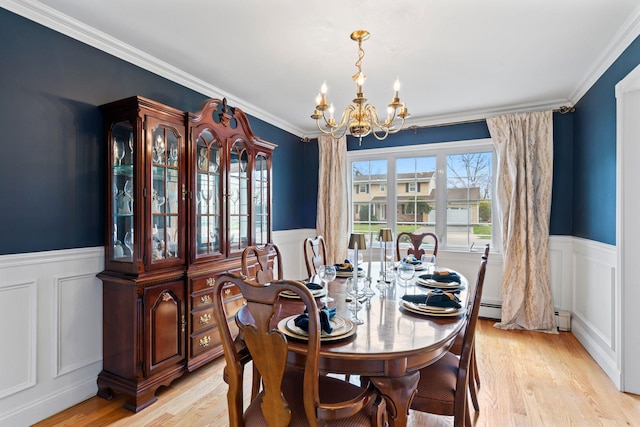 dining space featuring a wainscoted wall, a chandelier, light wood-style flooring, and a decorative wall