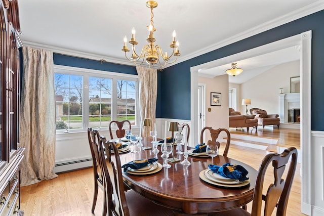 dining room with baseboard heating, ornamental molding, a notable chandelier, and light wood finished floors