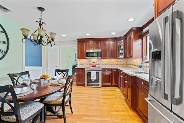 kitchen with visible vents, a sink, light wood-style floors, a chandelier, and appliances with stainless steel finishes