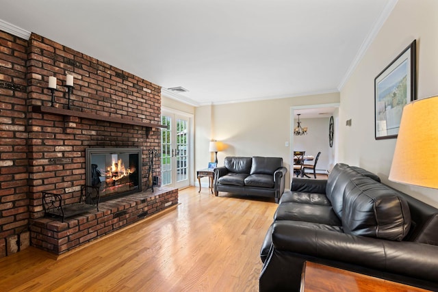 living room with ornamental molding, wood finished floors, visible vents, and a fireplace