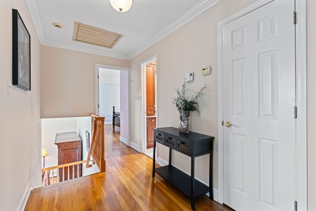 hall with baseboards, ornamental molding, an upstairs landing, and light wood finished floors