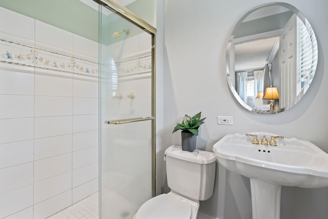 bathroom with toilet, a sink, and a stall shower