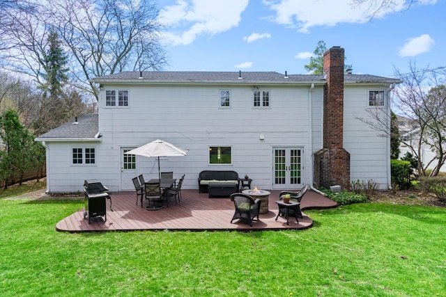 back of property featuring a wooden deck, a yard, french doors, and a chimney
