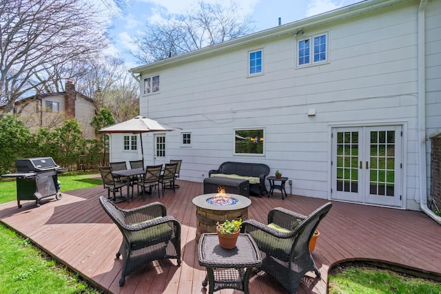 back of property with a wooden deck, french doors, outdoor dining space, and an outdoor fire pit