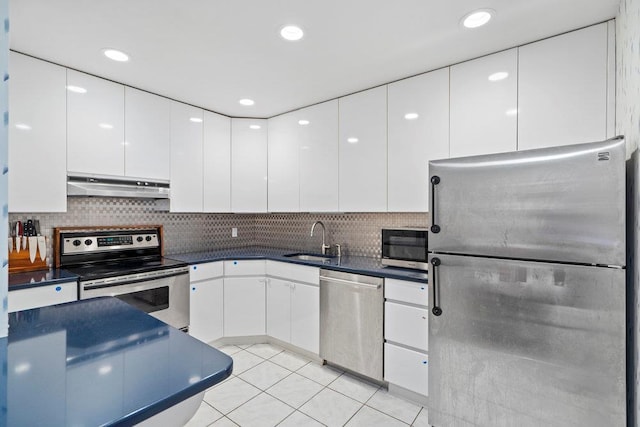 kitchen featuring white cabinets, stainless steel appliances, a sink, dark countertops, and under cabinet range hood