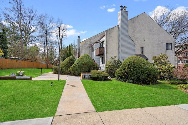 view of home's exterior featuring fence, a chimney, and a yard