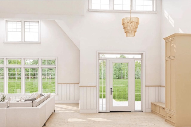 2215 Laurel Ave, Southold, NY 11971 - entrance foyer featuring a towering ceiling, a chandelier, a wainscoted wall, plenty of natural light, and light wood finished floors