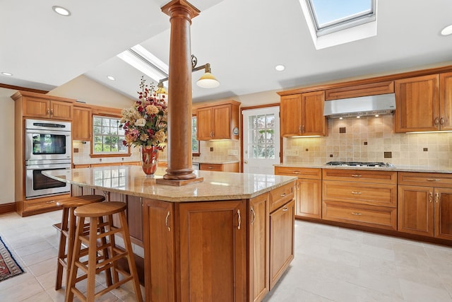 1449 Riverview Ave, Peekskill, NY 10566 - kitchen with extractor fan, decorative columns, stainless steel appliances, vaulted ceiling, and a kitchen island