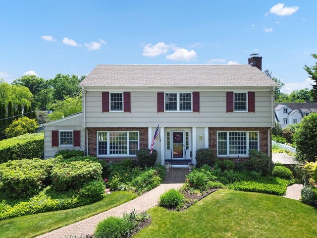 1449 Riverview Ave, Peekskill, NY 10566 - view of front of house with brick siding, a chimney, and a front lawn