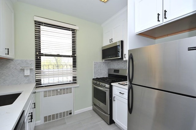 66 Rockledge Rd Unit 1B, Hartsdale, NY 10530 - kitchen with radiator heating unit, backsplash, light stone countertops, appliances with stainless steel finishes, and white cabinetry