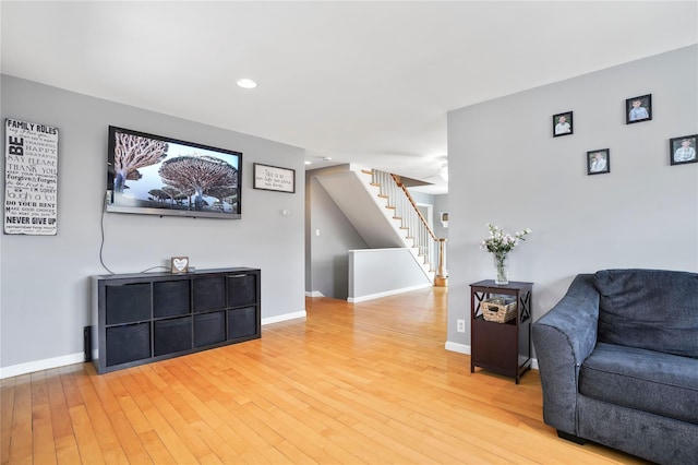 living area with baseboards, stairway, light wood finished floors, and recessed lighting
