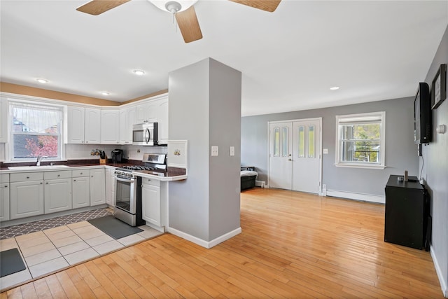kitchen with decorative backsplash, a sink, appliances with stainless steel finishes, light wood-style floors, and ceiling fan