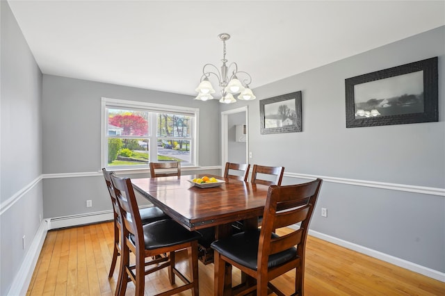 dining space featuring light wood-type flooring, a notable chandelier, baseboard heating, and baseboards