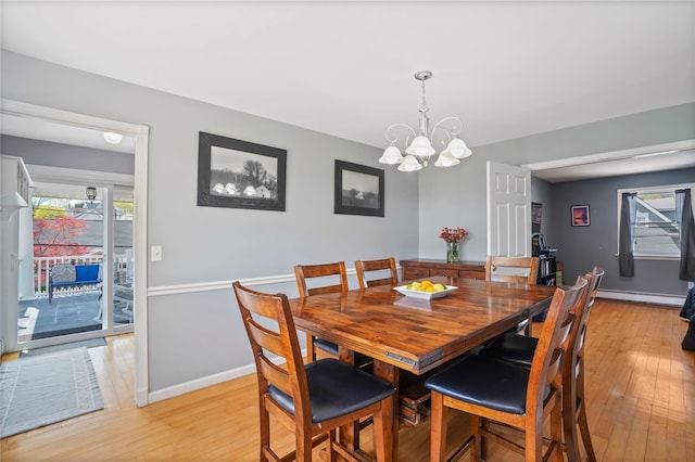 dining space with a baseboard radiator, light wood-style floors, a chandelier, and baseboards