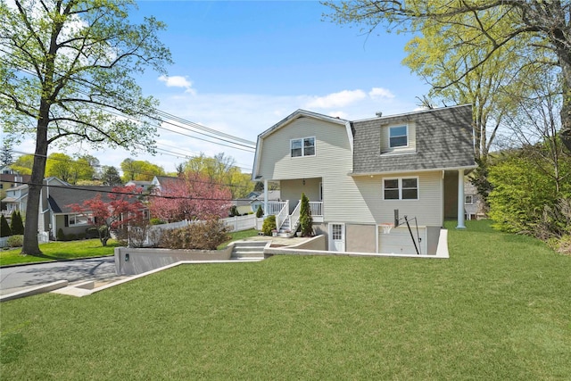 back of property with a lawn, a gambrel roof, and roof with shingles