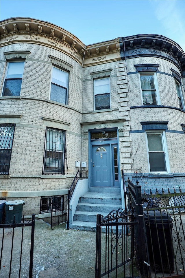 view of front facade featuring brick siding and fence private yard