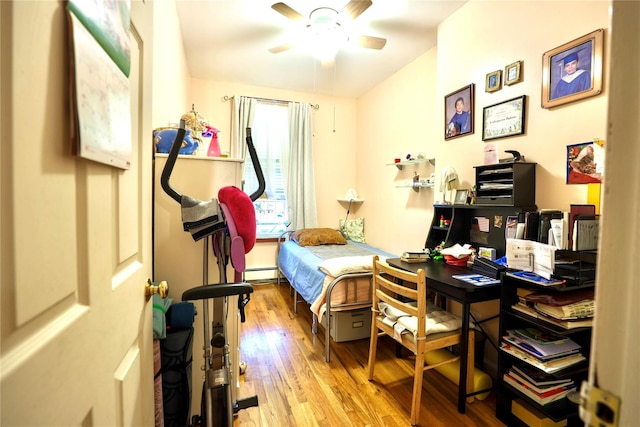 bedroom with a ceiling fan, a baseboard heating unit, and wood finished floors
