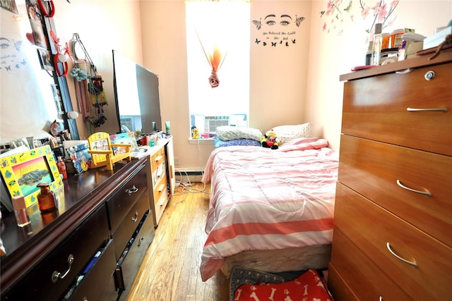 bedroom with light wood-style floors, cooling unit, and baseboard heating