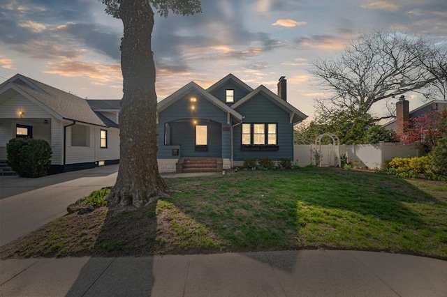 bungalow-style home featuring fence, a chimney, and a lawn