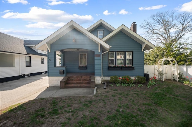 bungalow-style house with fence, a chimney, and a porch