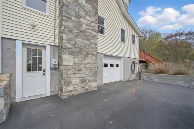 view of property exterior with an attached garage and aphalt driveway